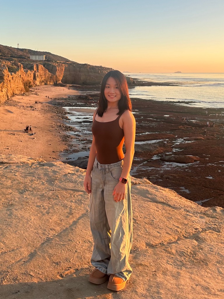 Jialu Gao standing by the ocean at sunset